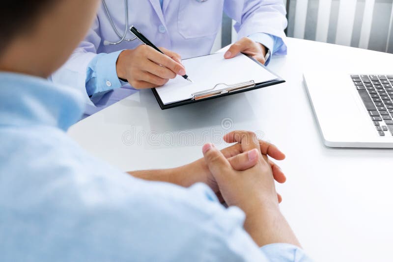 Ciérrese para arriba del paciente y del doctor que toman notas en un hospital o una clínica fotos de archivo Ciérrese para arriba del paciente y del doctor que toman notas en un hospital o una clínica fotos de archivo