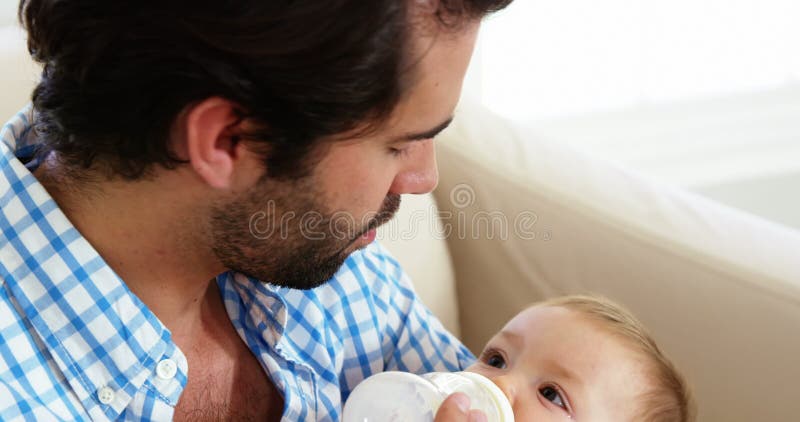 Ciérrese para arriba del padre feliz que cría con biberón a su bebé