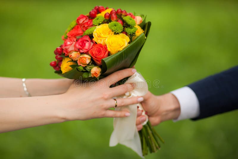 Ciérrese para arriba del ramo hermoso de flores frescas Manos del hombre y de la mujer novia feliz, novio sobre fondo del parque fotografía de archivo libre de regalías Ciérrese para arriba del ramo hermoso de flores frescas Manos del hombre y de la mujer novia feliz, novio sobre fondo del parque fotografía de archivo libre de regalías