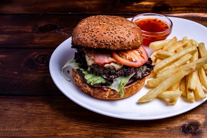 Ciérrese para arriba papases fritas en el apoyo del papel con las hamburguesas hechas en casa frescas, servido con el tarro de sa imagenes de archivo Ciérrese para arriba papases fritas en el apoyo del papel con las hamburguesas hechas en casa frescas, servido con el tarro de sa imagenes de archivo