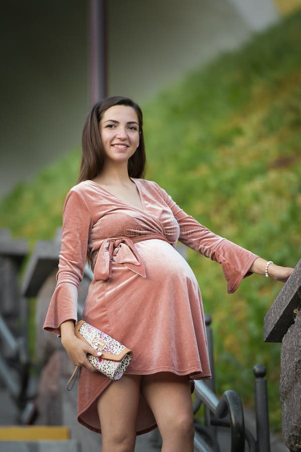 Ciężarna dziewczyna pozuje na schodkach brunetka w velor sukni W na wolnym powietrzu fotografia stock Ciężarna dziewczyna pozuje na schodkach brunetka w velor sukni W na wolnym powietrzu fotografia stock