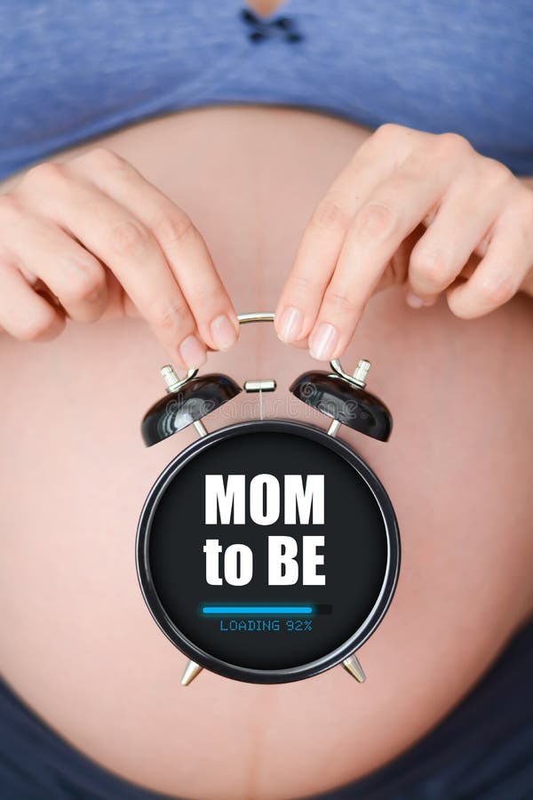 Ciężarna mama trzyma budzika z ładowanie barem zdjęcia stock Ciężarna mama trzyma budzika z ładowanie barem zdjęcia stock
