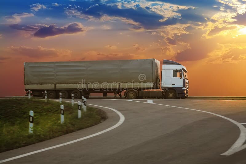 Ciężarówka iść na autostradzie na zmierzchu obraz stock Ciężarówka iść na autostradzie na zmierzchu obraz stock
