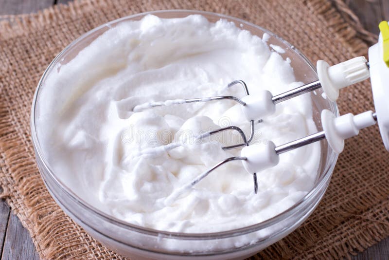 Claras de huevo azotadas y otros ingredientes para la crema en la tabla de madera, primer foto de archivo Claras de huevo azotadas y otros ingredientes para la crema en la tabla de madera, primer foto de archivo