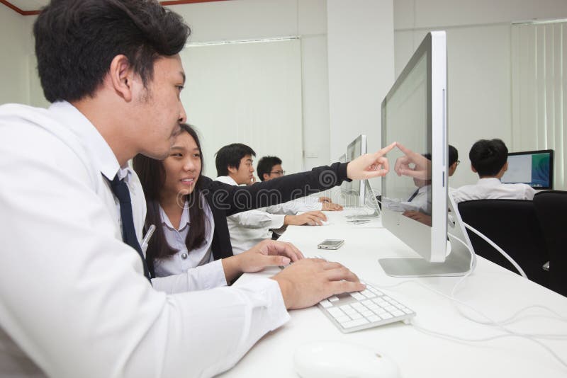 A class of students in front of their screens study computer science. royalty free stock images