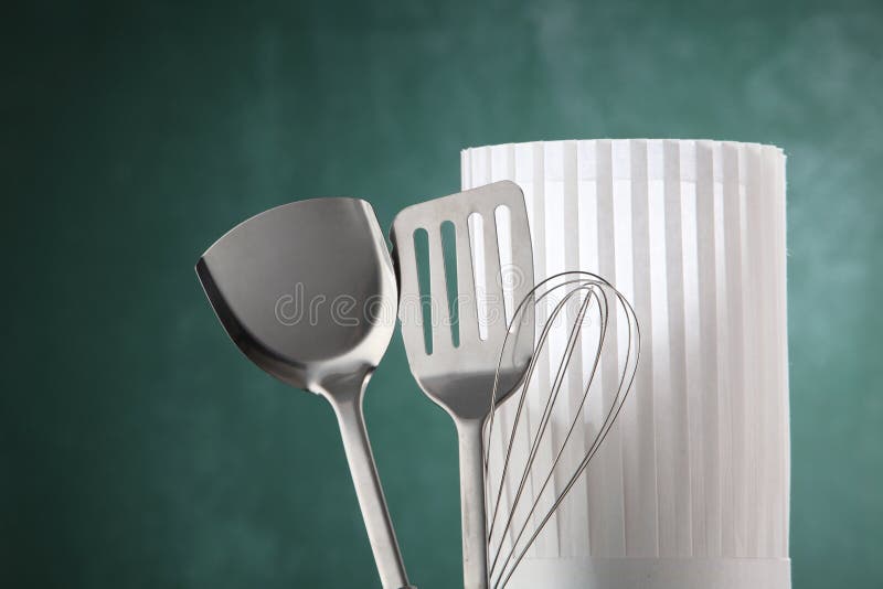 Kitchen utensil and the chef's hat in front of the chalkboard. Kitchen utensil and the chef's hat in front of the chalkboard