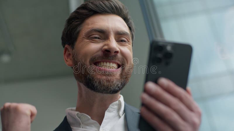 Classer heureux souriant caucasien moyen âge homme d'affaires gagnant avec téléphone mobile en ligne pari casino victoire dans banque de vidéos