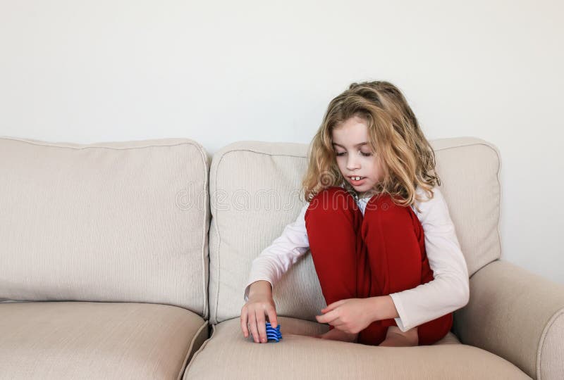 Classic autism behavior: a child sitting alone on a couch, stacking toysinstead of playing with them in the usual manner. Classic autism behavior: a child sitting alone on a couch, stacking toysinstead of playing with them in the usual manner