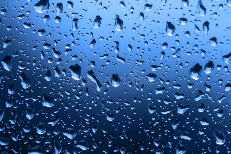 Classic Blue background. Color of the year 2020. The texture of rain drops on the glass close-up. Macro transparent water drops on