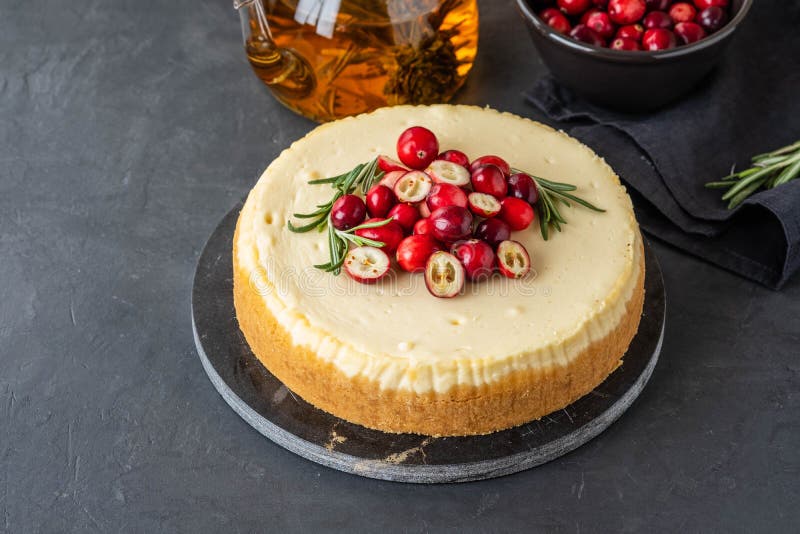 Classic cheesecake with cranberries and rosemary on a dark background. Winter version of cheesecake. Christmas stock image Classic cheesecake with cranberries and rosemary on a dark background. Winter version of cheesecake. Christmas stock image