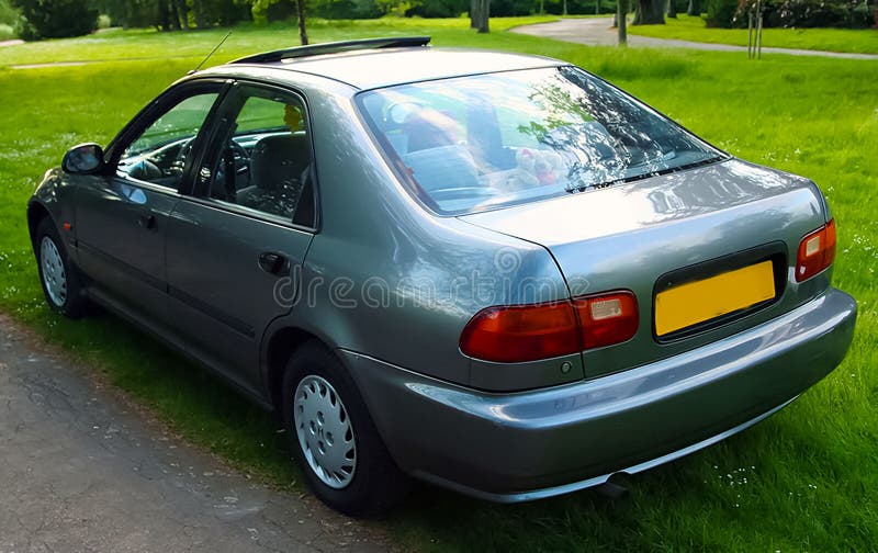 Classic dark silver sedan is parked on a grassy patch with trees and foliage in the background, the scene conveys a peaceful stock images
