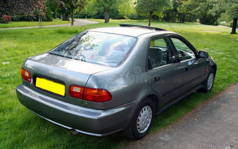Classic dark silver sedan is parked on a grassy patch with trees and foliage in the background, the scene conveys a peaceful royalty free stock photography