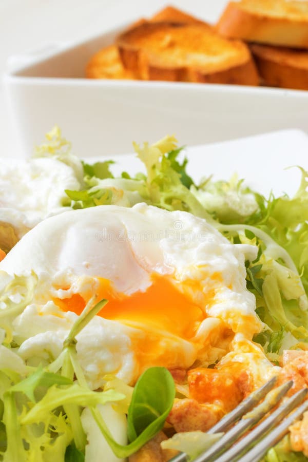 Great Salade Lyonnaise, French classic salad. Eggs, bacon, toasts.