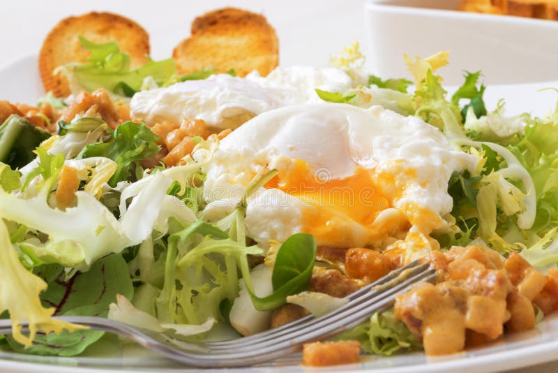 Great Salade Lyonnaise, French classic salad. Eggs, bacon, toasts.