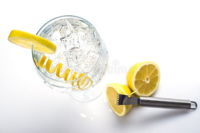 Classic gin and tonic with a lemon twist. Gin and tonic in a highball cup garnished with a lemon wedge and twist stock images Classic gin and tonic with a lemon twist. Gin and tonic in a highball cup garnished with a lemon wedge and twist stock images