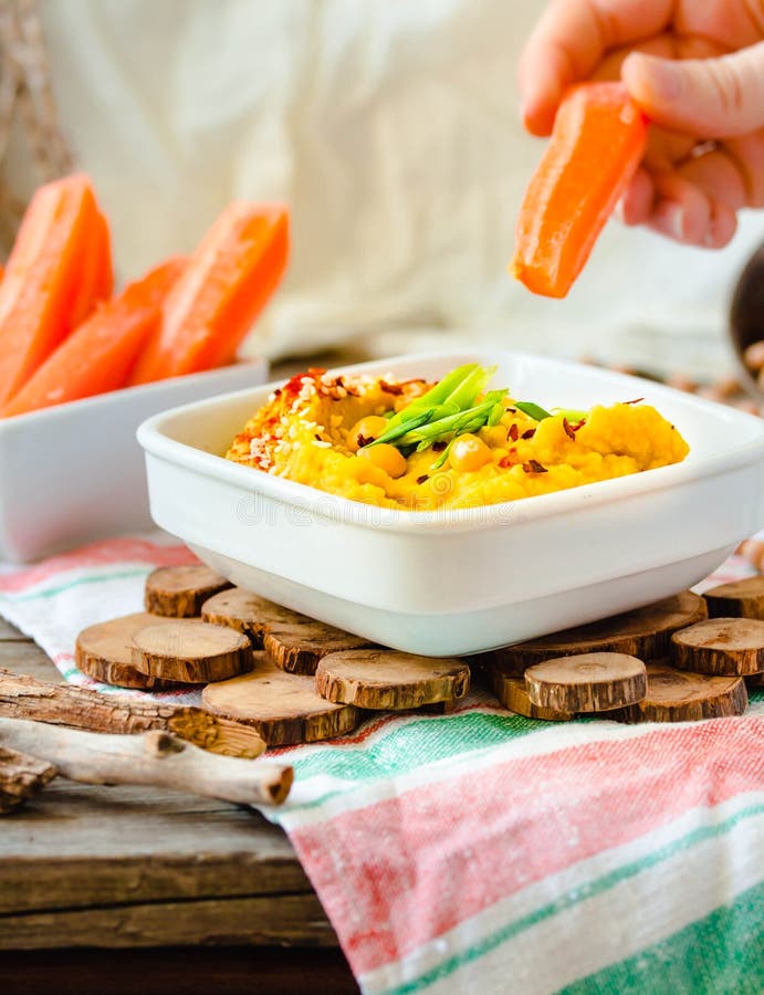 Classic hummus with herbs, olive oil in a ceramic bowl, served with carrot sticks. Vintage background. Traditional Middle Eastern royalty free stock images Classic hummus with herbs, olive oil in a ceramic bowl, served with carrot sticks. Vintage background. Traditional Middle Eastern royalty free stock images