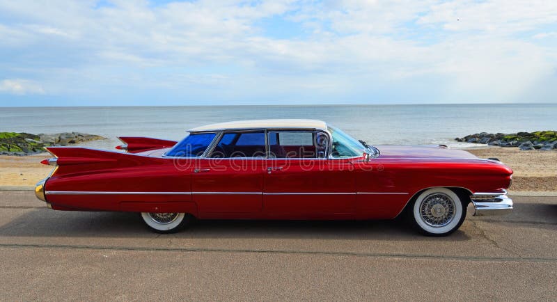 Classic Red 1950`s 4 door Cadillac  motor car parked on seafront promenade.