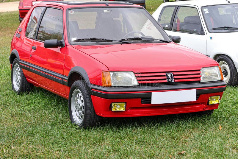 Classic red sports car Peugeot 205 GTi standing on the green grass