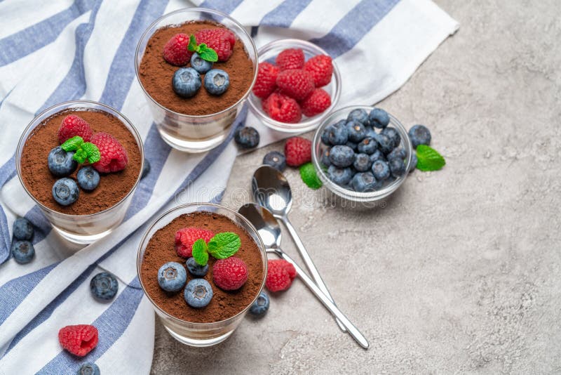 Classic tiramisu dessert with blueberries and raspberries in a glass cup on concrete background stock images Classic tiramisu dessert with blueberries and raspberries in a glass cup on concrete background stock images