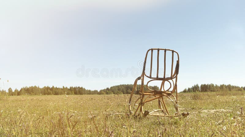 Classic Wooden Rocking Chair Outdoors in a Field among Yellow Grass