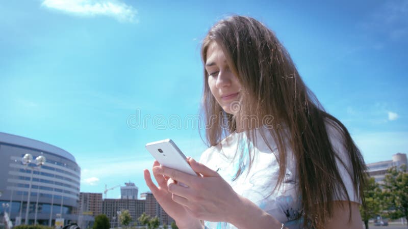 Clausura de una mujer que usa el teléfono al aire libre leyendo mensajes de sus amigos y buscando tiendas en línea para ir de comp