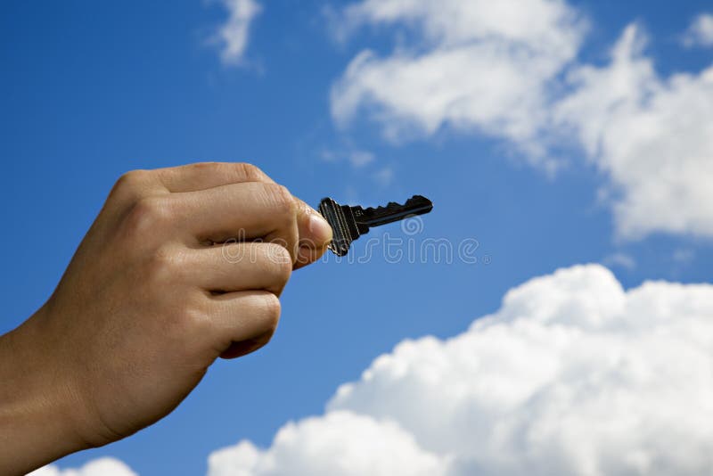The key to success when the sky is the limit. Key in hand against blue sky and clouds. The key to success when the sky is the limit. Key in hand against blue sky and clouds.