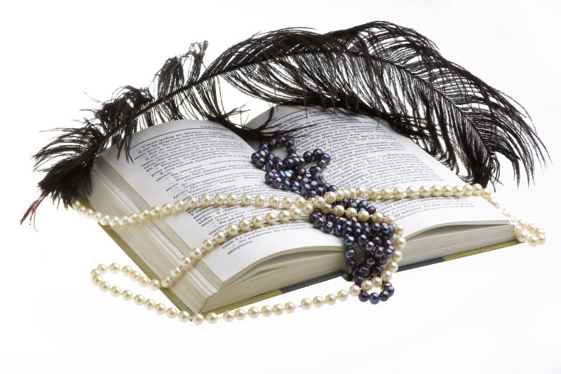 Open book on white background, beads and feather lying on the book. Open book on white background, beads and feather lying on the book