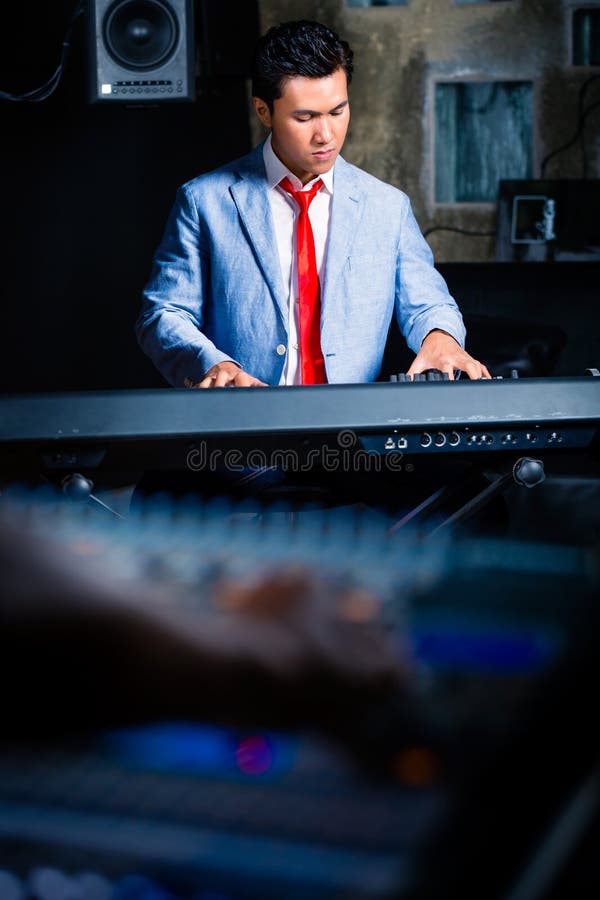 Claviste asiatique jouant dans le studio d'enregistrement photo stock Claviste asiatique jouant dans le studio d'enregistrement photo stock