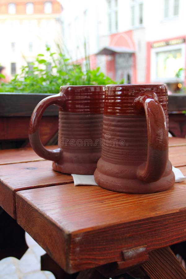 Two traditional clay beeg mugs on wooden table in cafe. Two traditional clay beeg mugs on wooden table in cafe