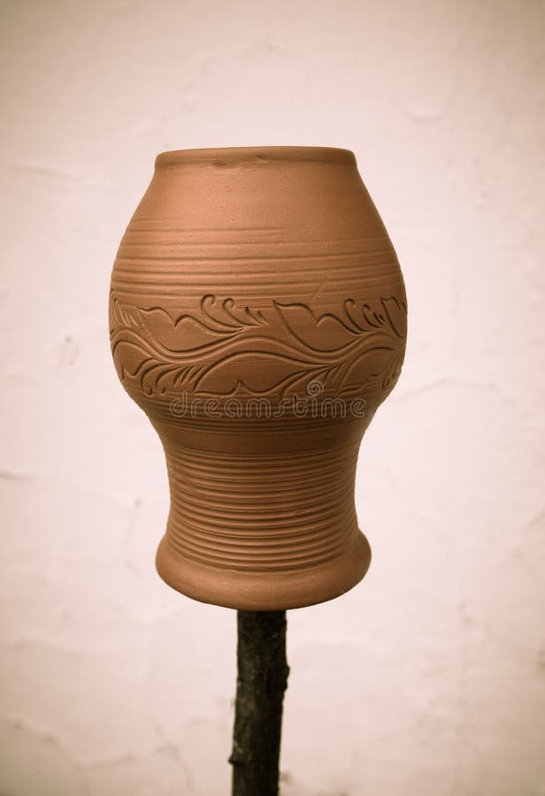 Clay Pot with a Pattern on a Wooden Stick on a Light Background. Stock