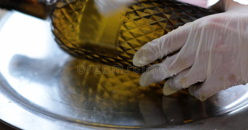 Clean and degrease surface of patterned glass wine bottle closeup. Use rag with cleaning agent, wash with protective gloves, scrub with hands. Removing stains and dirt, prepare bottle for new applying. Degrease video