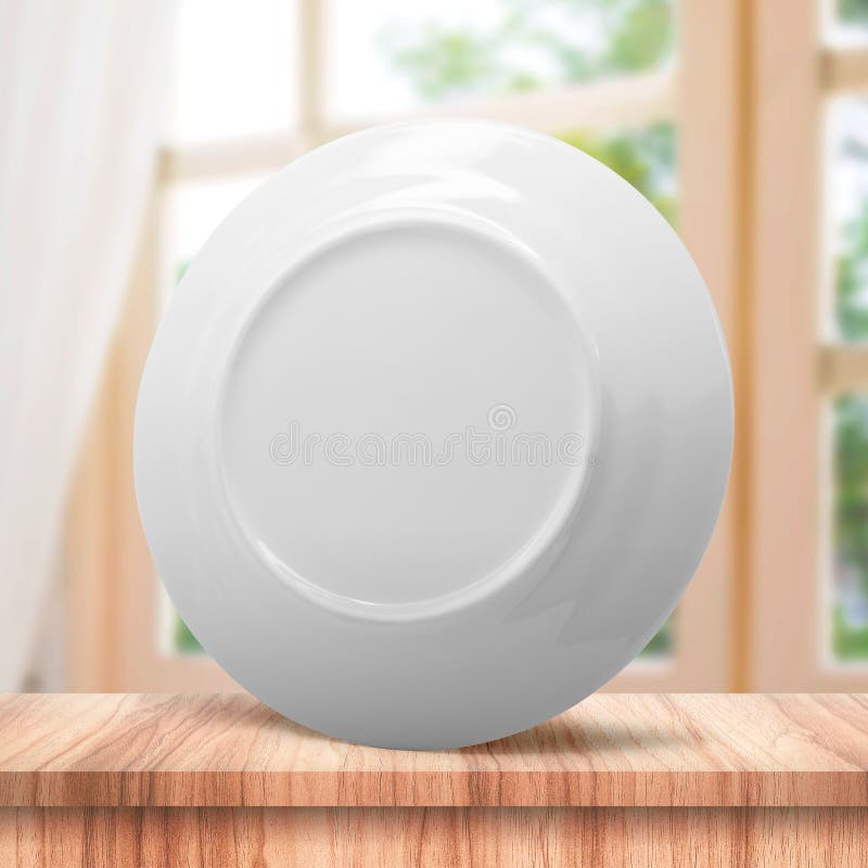 Clean dish or ceramic plate on modern kitchen background with blank dishware concept. White dish template place on wooden table royalty free stock image