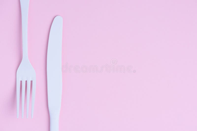 Clean new white knife and fork creative flat lay on pink paper background royalty free stock photography