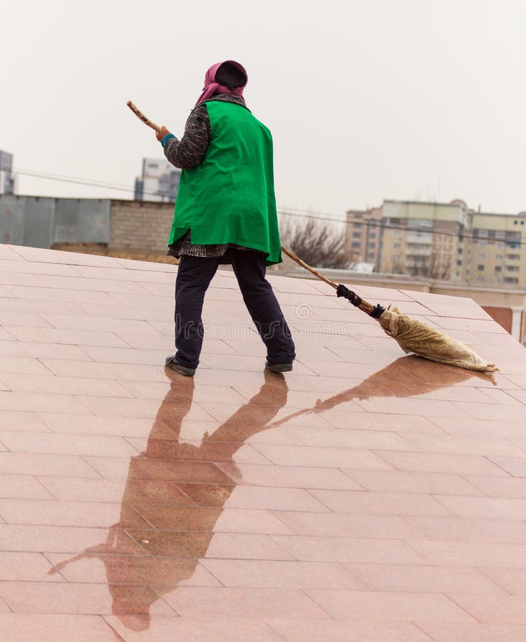 A Cleaning Lady is Sweeping the Road with a Broom Stock Image Image