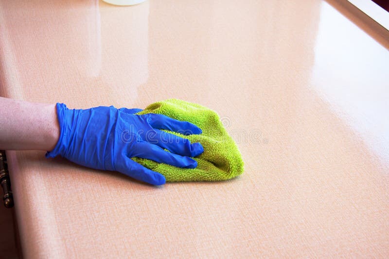 Closeup of hand with purple latex glove cleaning kitchen countertop with green microfiber cloth. Closeup of hand with purple latex glove cleaning kitchen countertop with green microfiber cloth