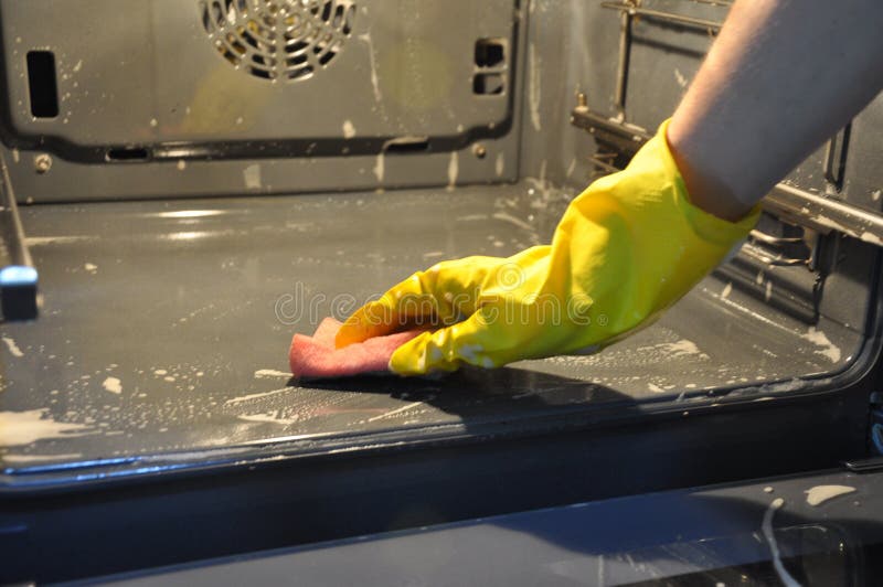 Cleaning the oven in the kitchen. hand in a yellow economic glove