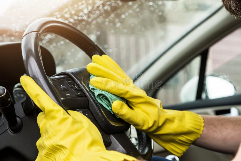 Cleaning service. Man in uniform and yellow gloves washes a car interior in a car wash.