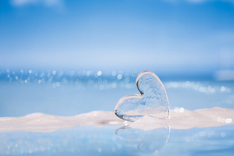 Clear glass heart on white sand beach glitter glass and reflec