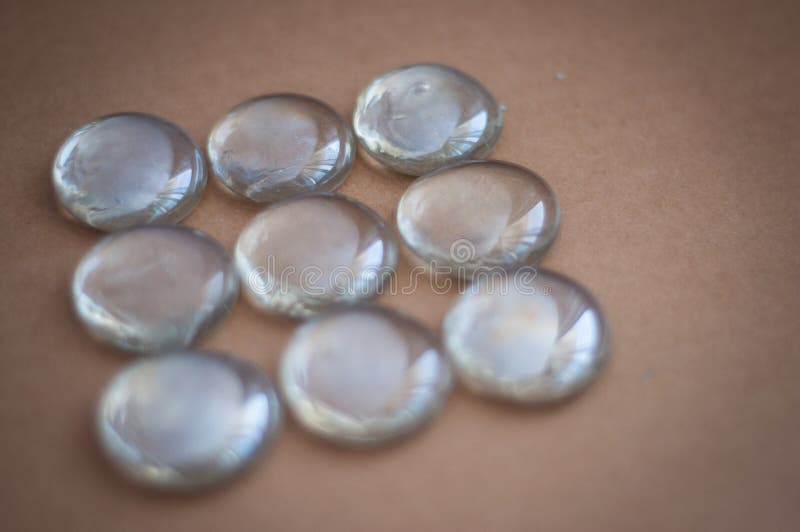 Clear Marbles with Light Reflections on a Brown Background. Stock Image