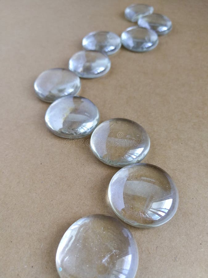 Clear Marbles with Light Reflections on a Brown Background. Stock Image