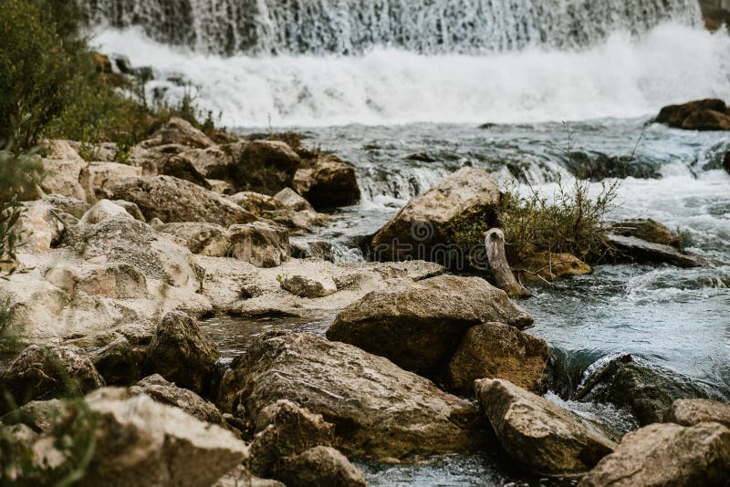 Clear water cascades over an array of large, irregular rocks, creating a dynamic river scene. royalty free stock images