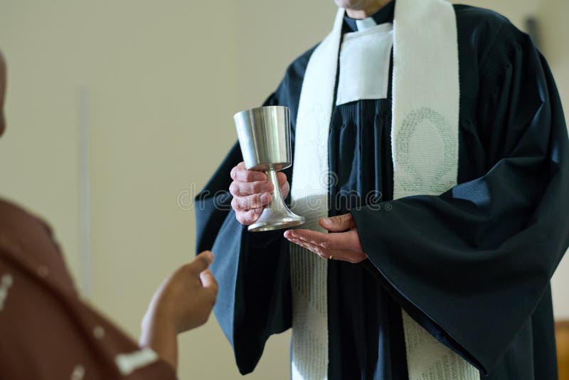 Clergyman of Catholic church holding cup with wine for oblation rite