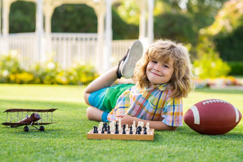 Clever happy child playing chess in backyard outdoor. stock photography