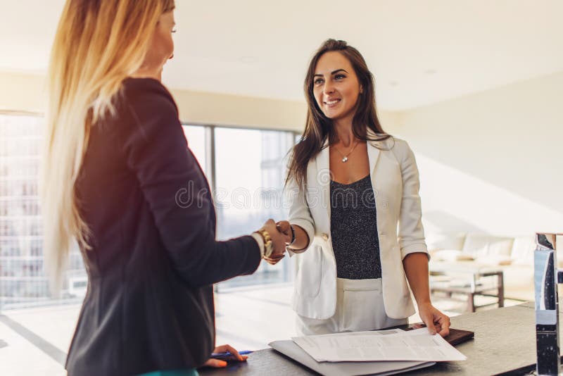 Client féminin serrant la main au vrai agent immobilier acceptant de signer un contrat se tenant en nouveau studio moderne