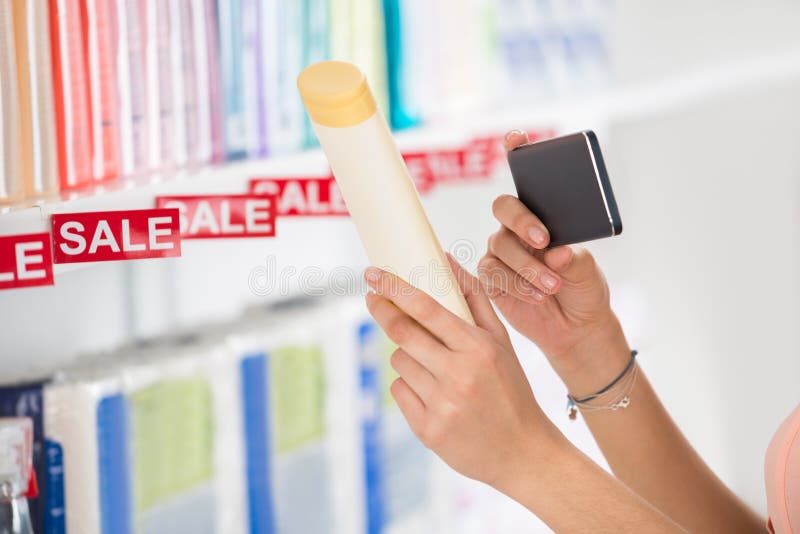 Cropped image of female customer photographing cosmetic product in supermarket. Cropped image of female customer photographing cosmetic product in supermarket