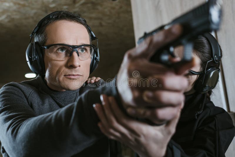 Hombre con ropa táctica disparando desde una pistola, volviendo a cargar la  pistola y apuntando al objetivo en la zona de tiro de puerta abierta  Fotografía de stock - Alamy