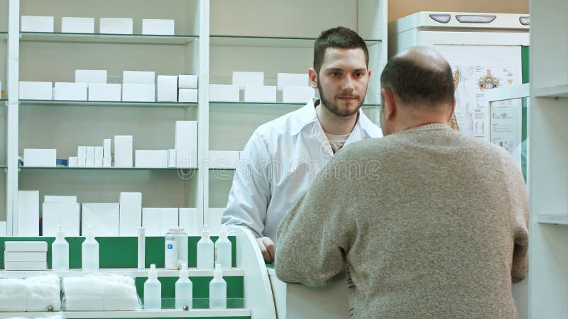 Young pharmacist and senior men customer with drug and prescription at drugstore. Professional shot in 4K resolution. 081. You can use it e.g. in your commercial video, business, presentation, broadcast video. Young pharmacist and senior men customer with drug and prescription at drugstore. Professional shot in 4K resolution. 081. You can use it e.g. in your commercial video, business, presentation, broadcast video.