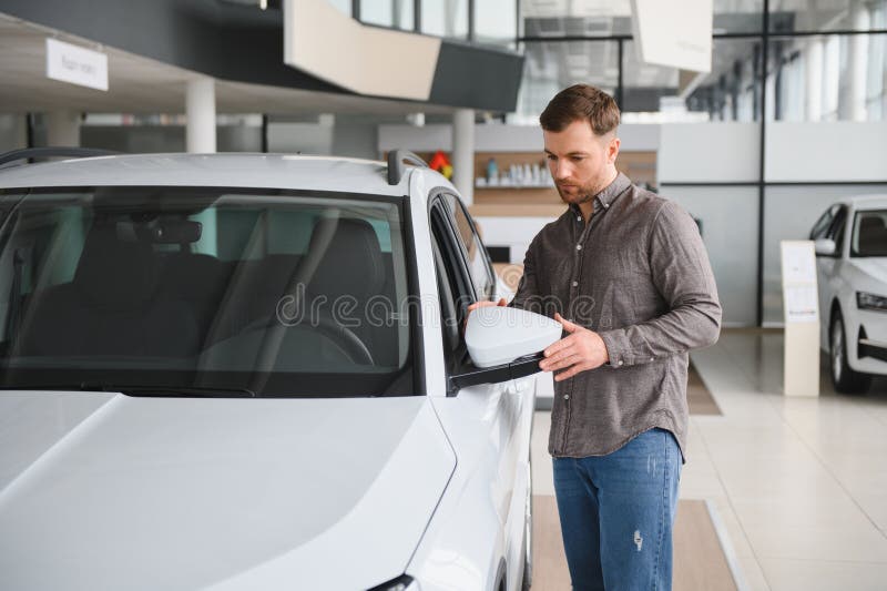 Cliente examinando el espejo retrovisor del coche nuevo en el concesionario imagen de archivo libre de regalías