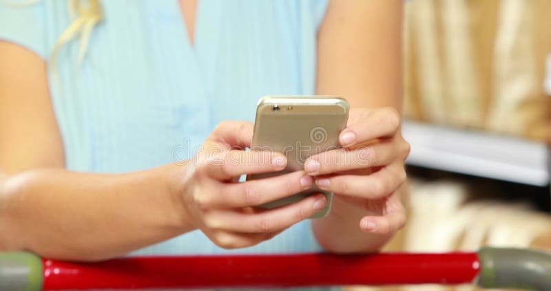 Cliente femminile che manda un sms mentre comperando