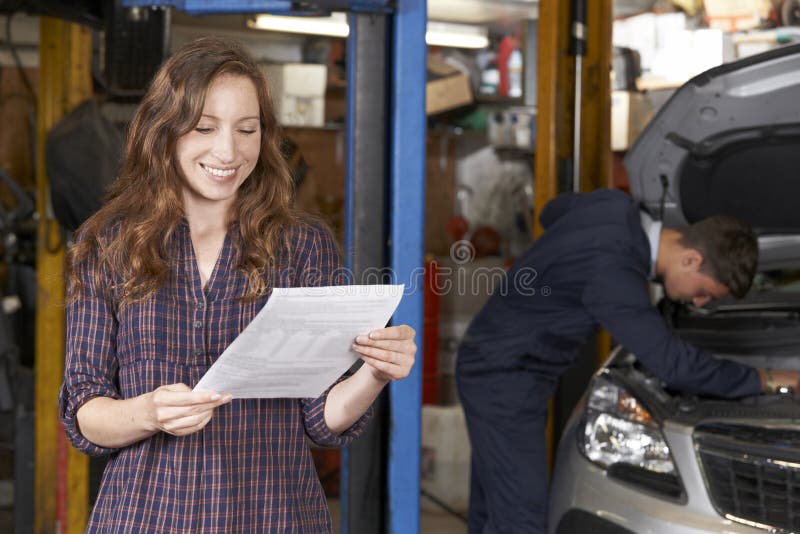 Cliente femminile nell'officina riparazioni automatica soddisfatta con Bill For Car